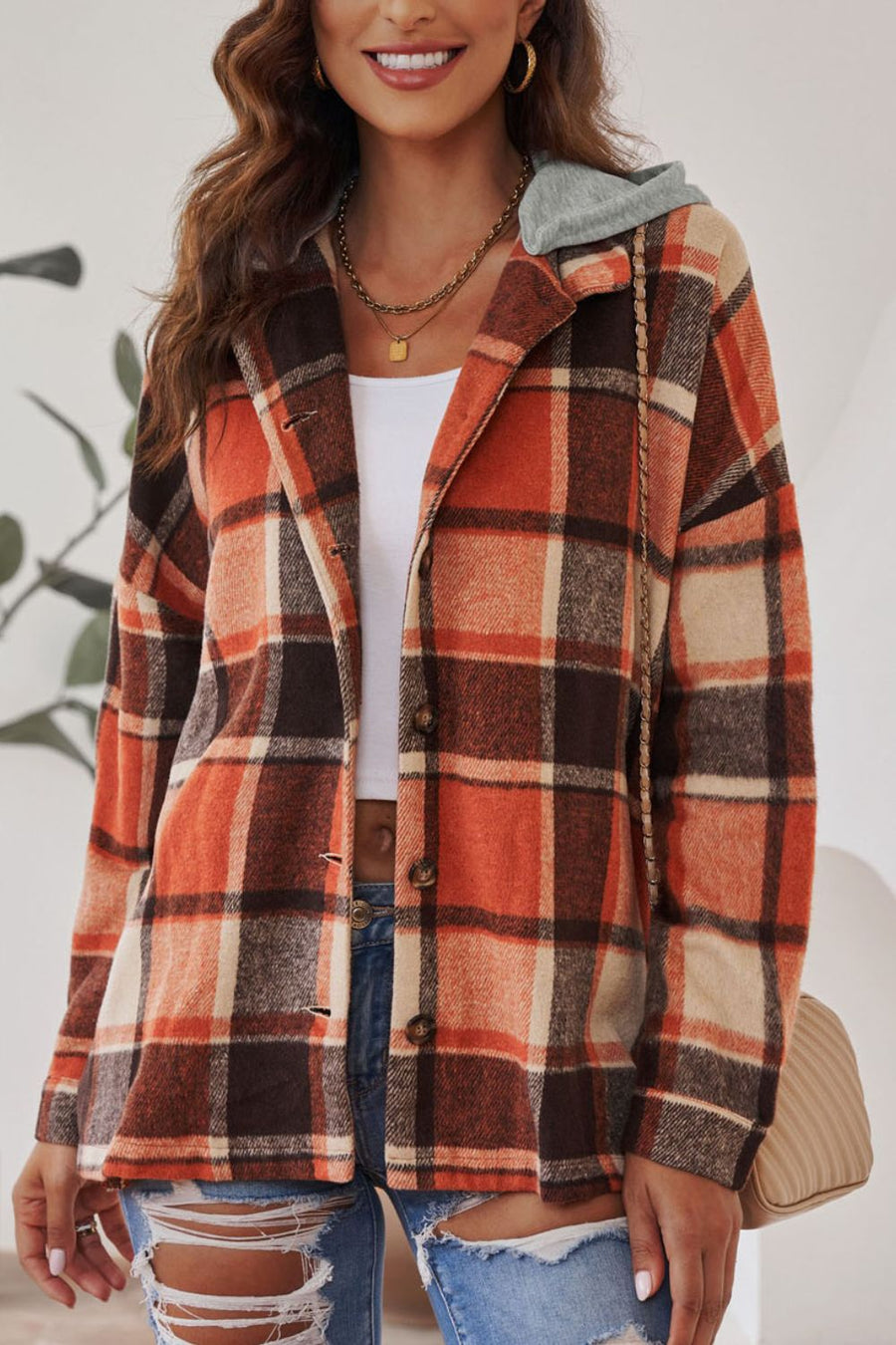 Plaid hooded shacket in orange, tan, and brown with button front and relaxed fit.