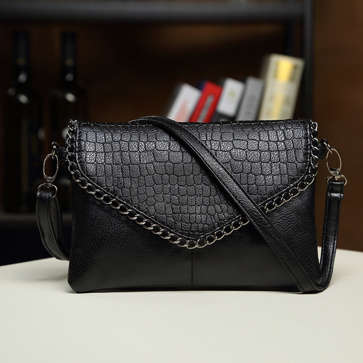 crossbody bag in black featuring chain strap detail and structured fit