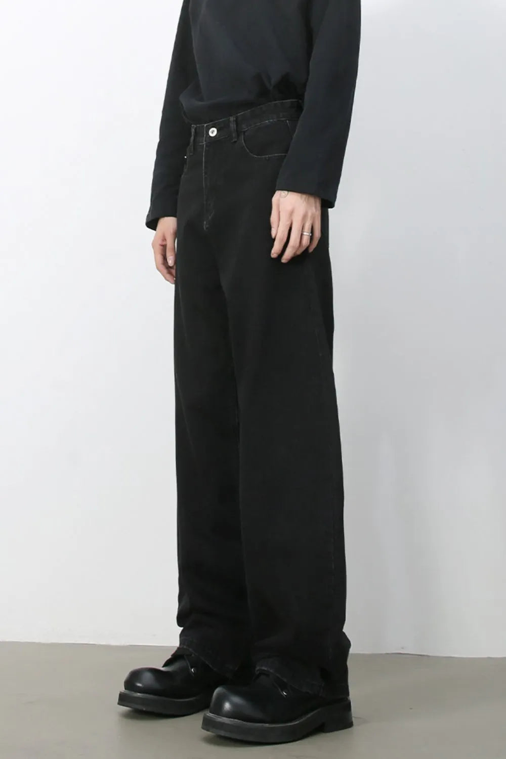 Black denim balloon trousers with a relaxed fit and visible stitching detail.