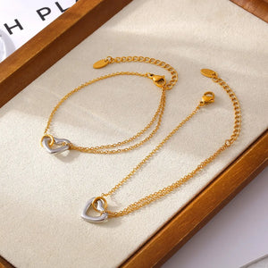Gold two-tone heart charm chain bracelet with delicate double chains.