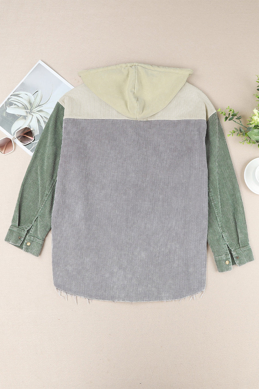 Colorblock corduroy hooded utility jacket in green, gray, and tan with frayed hem.