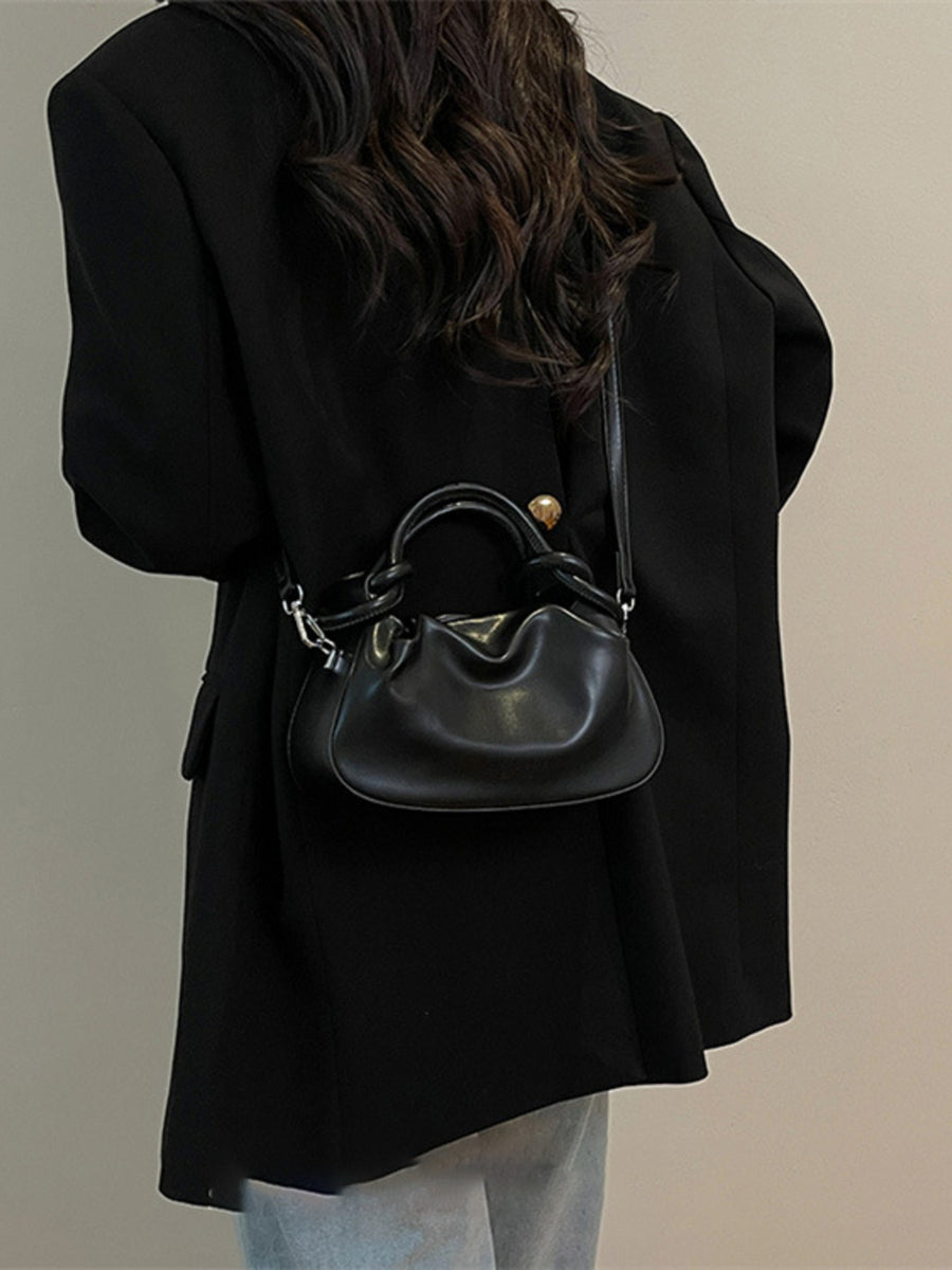 Black ruched crossbody bag with knot handle and adjustable strap.