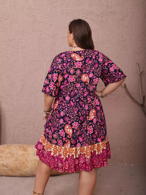 Plus-size navy floral flutter dress with ruched waist and tiered ruffle hem.