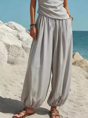 Gray one-shoulder top and wide-leg pants set with cinched ankles, worn with sandals.