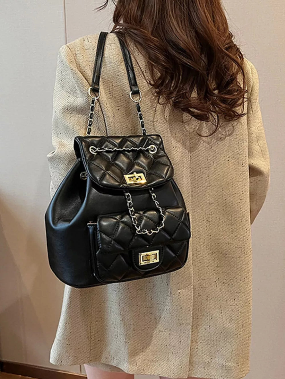 Black quilted mini backpack with chain straps and gold hardware.