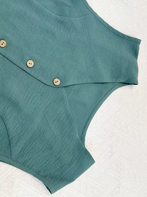 Turquoise cropped vest with button details and textured fabric.