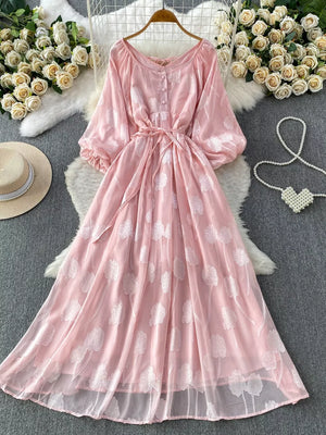Pink chiffon maxi dress with floral embroidery, puff sleeves, button-down front, and belted waist.