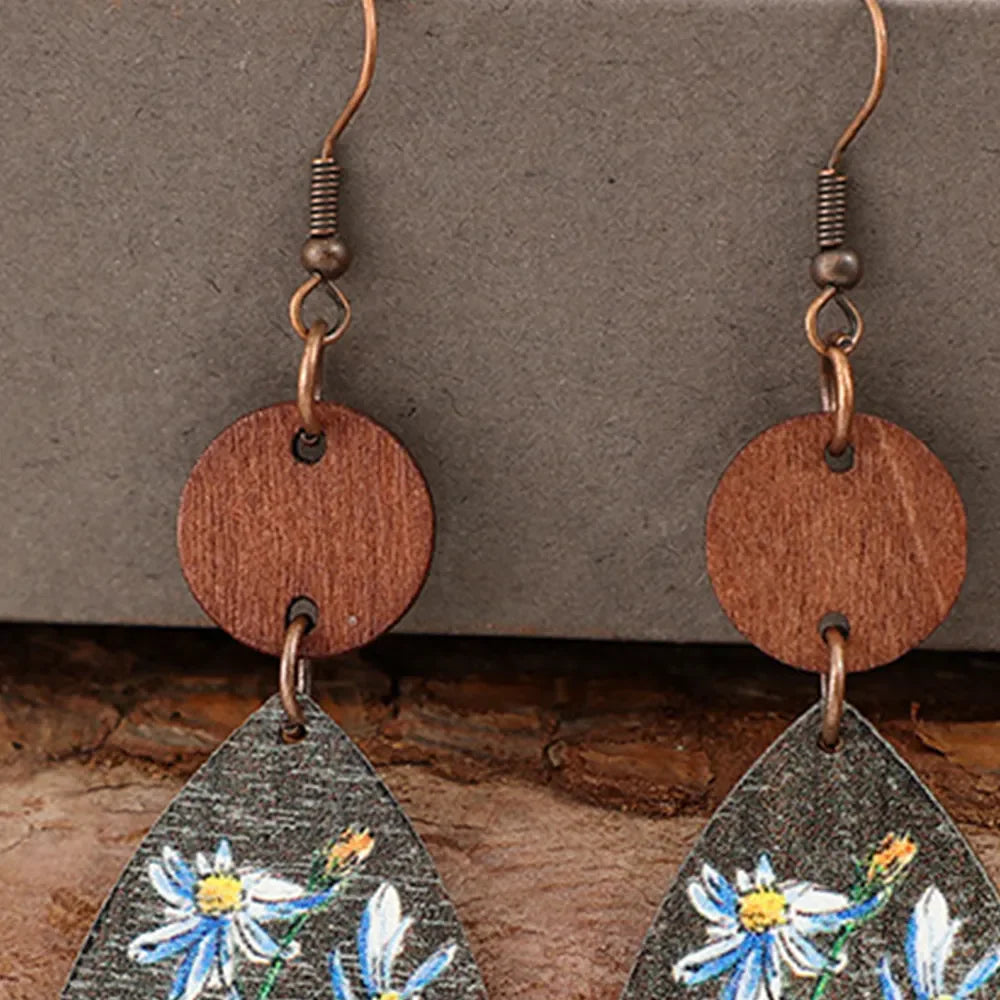 Botanical wood teardrop earrings with blue floral print and copper hooks.