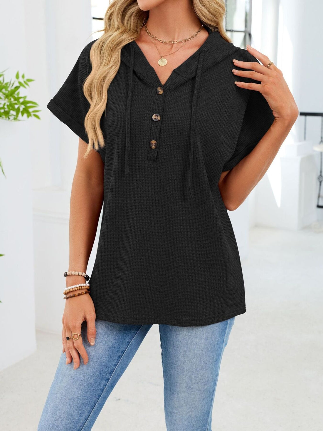 Black waffle knit short sleeve hooded top with button placket and drawstring.