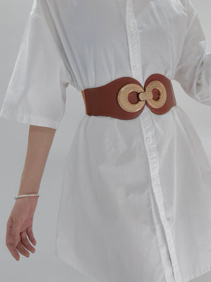 Caramel elastic belt with gold interlocking circle buckle cinching a white shirt