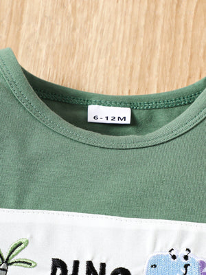Green cotton baby tee with dinosaur embroidery and white panel detail.