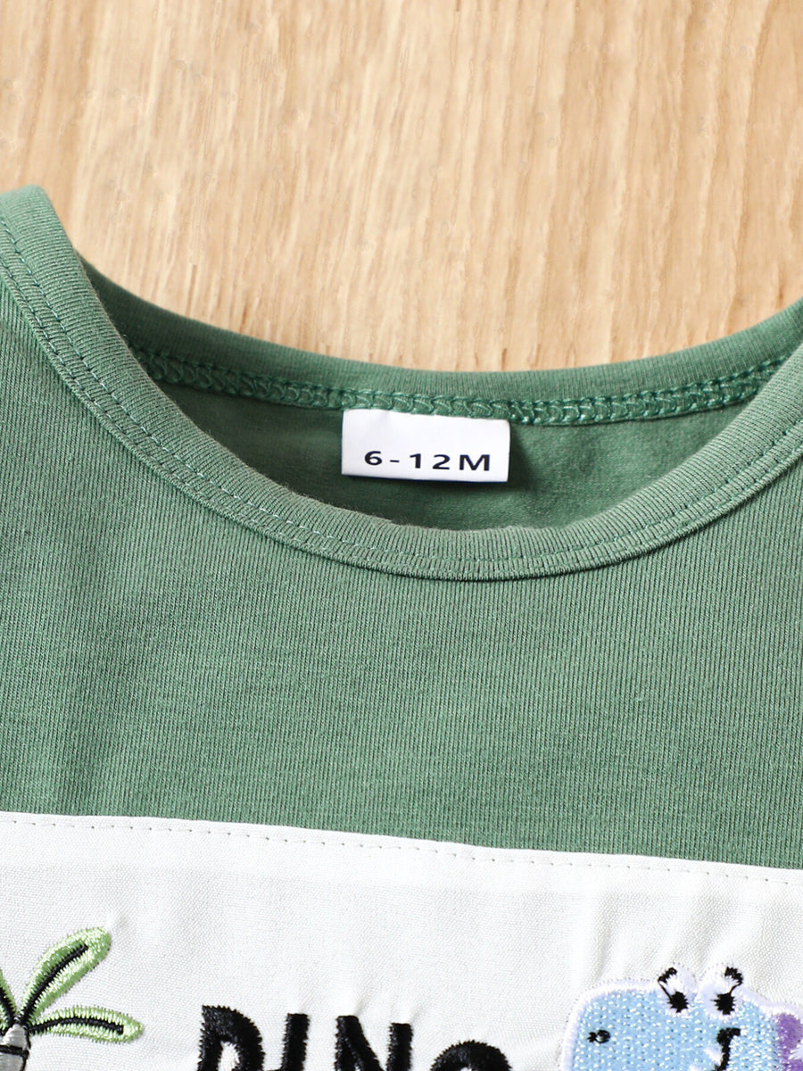 Green cotton baby tee with dinosaur embroidery and white panel detail.