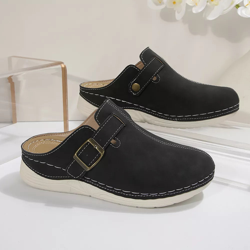 Black slip-on flats with buckle accent and contrast stitching.