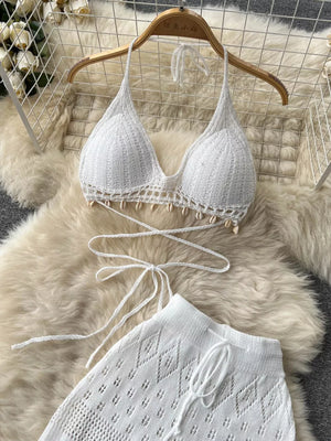 White crochet halter bikini top with shell trim and matching wide-leg pants.