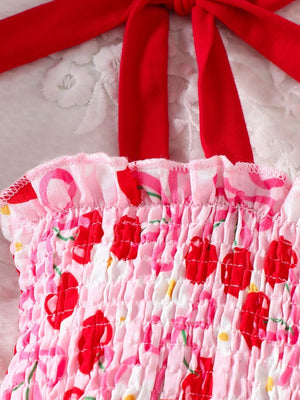 Toddler smocked dress with cherry print, ruffled neckline, and red tie straps.