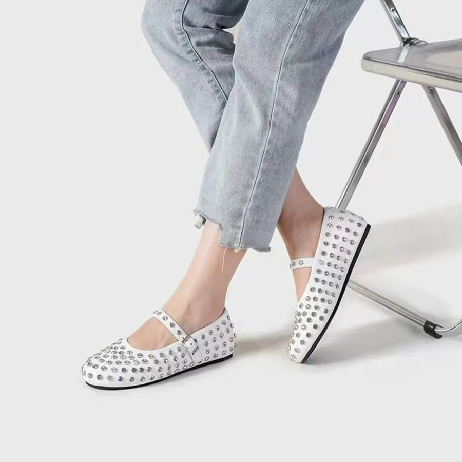 White studded Mary Jane flats with ankle strap, styled with cropped jeans.