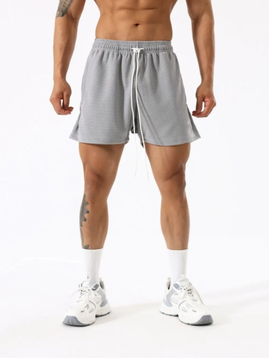 Gray athletic drawstring lounge shorts with white tie and textured fabric.