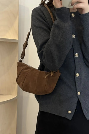 Brown suede crescent shoulder bag with pleated detail and knotted strap.