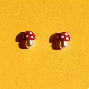 Whimsical mushroom stud earrings in deep red with white polka dots and pearl stems.