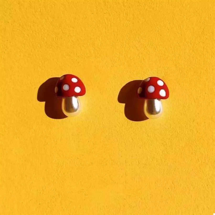 Whimsical mushroom stud earrings in deep red with white polka dots and pearl stems.