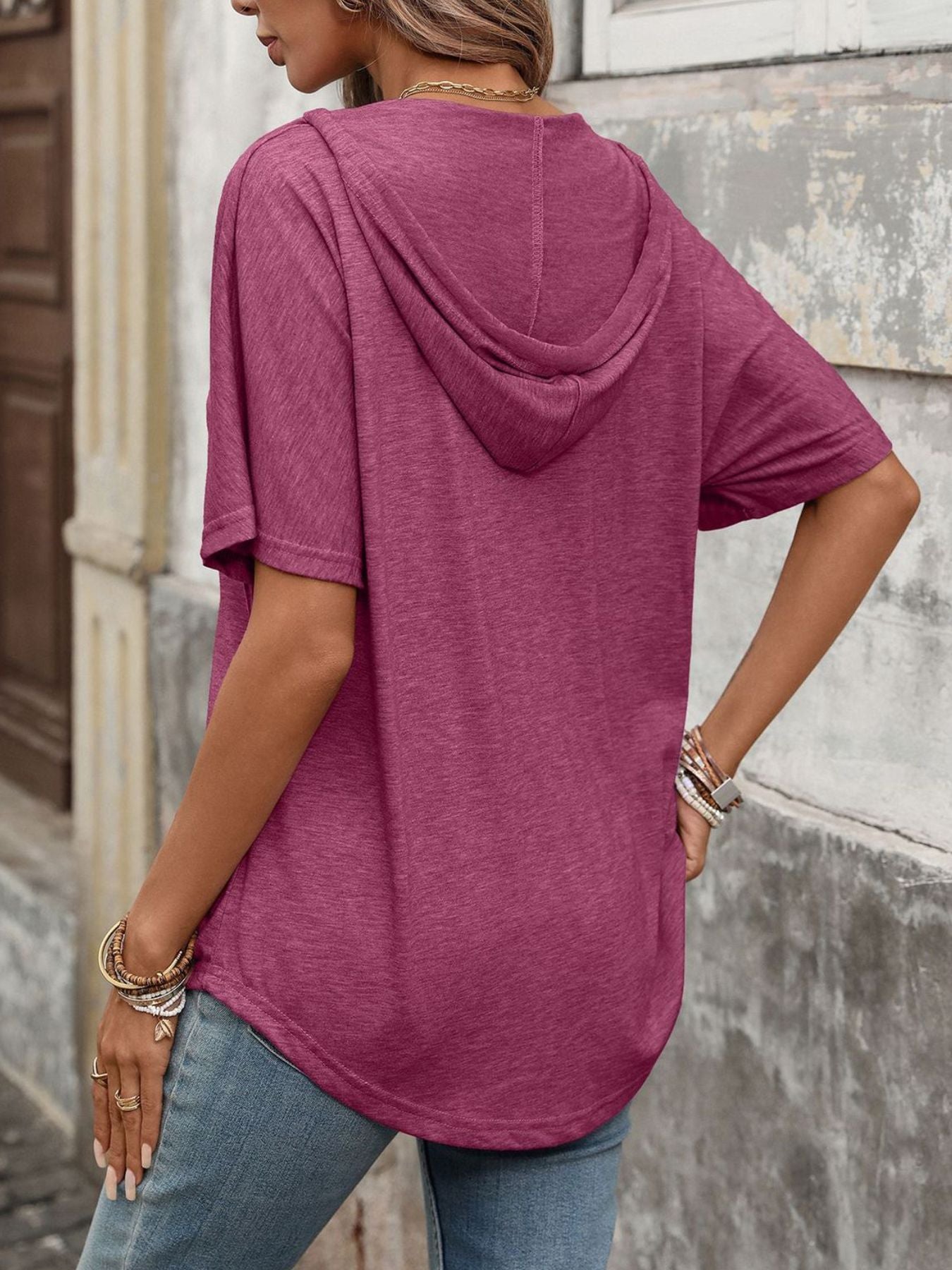 Burgundy relaxed short sleeve hooded t-shirt with a curved hem, worn by a woman.