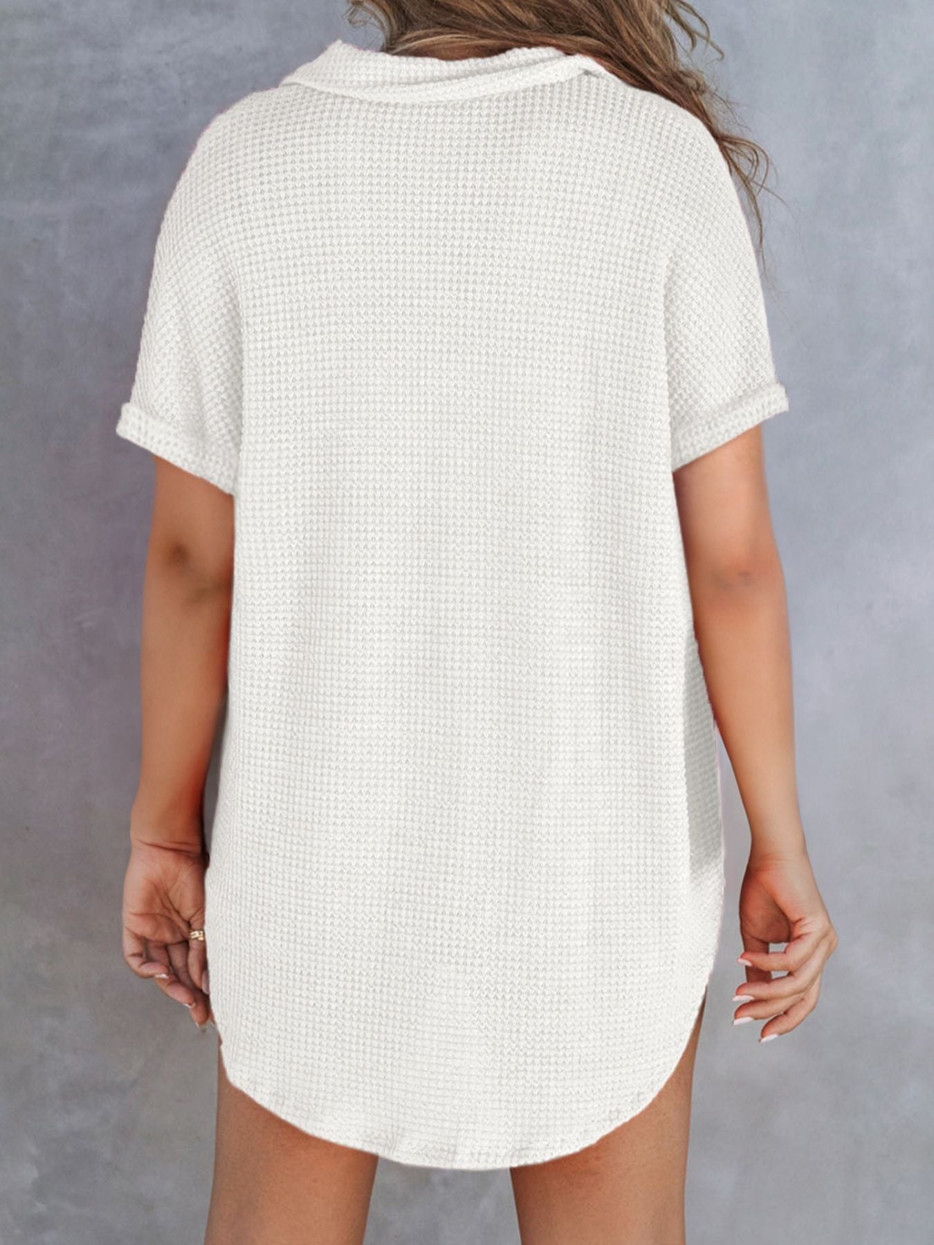 White waffle knit button-up shirt with cuffed short sleeves and curved hem.