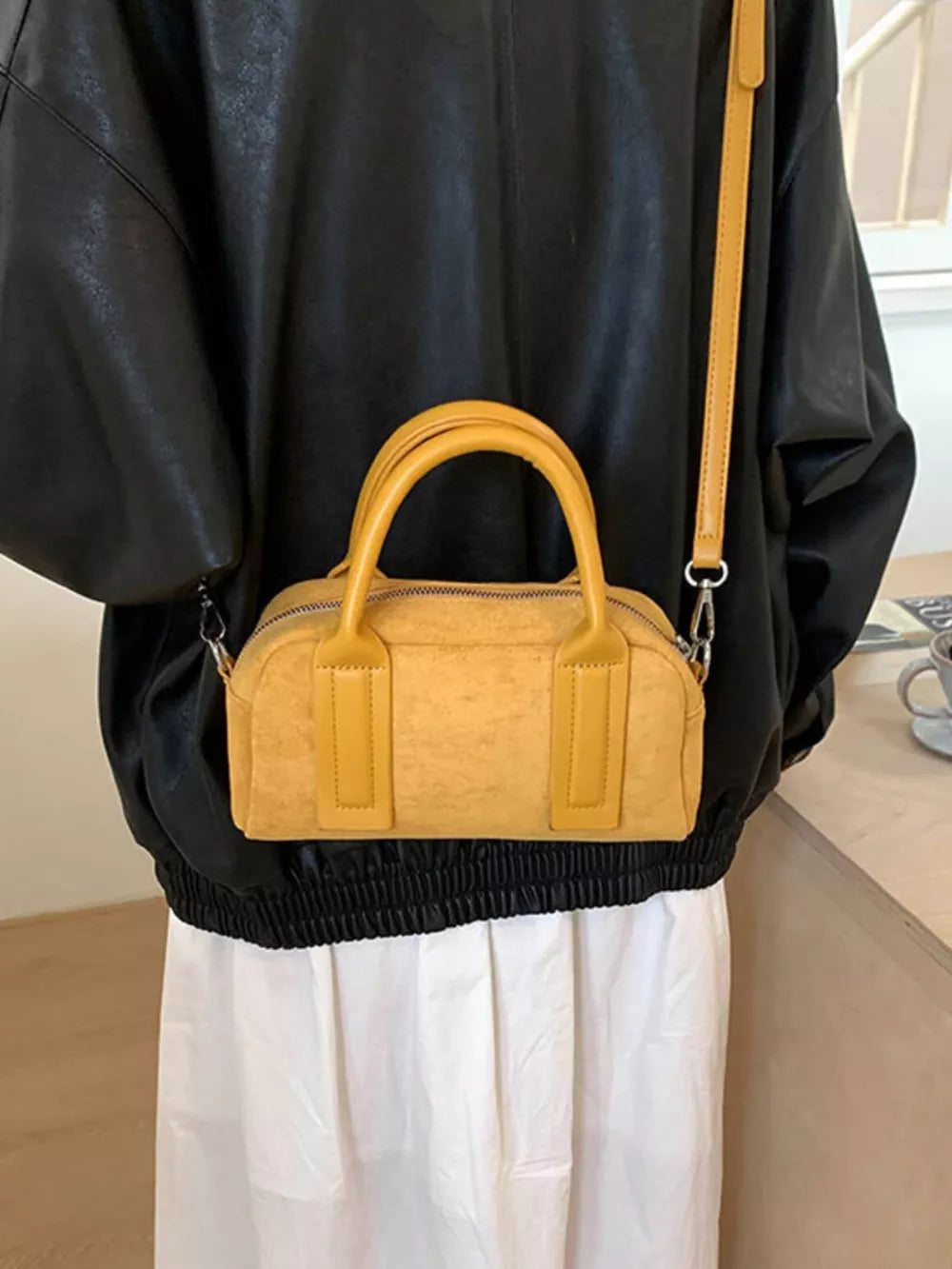 Chic yellow suede crossbody bag with top handles and a long strap.