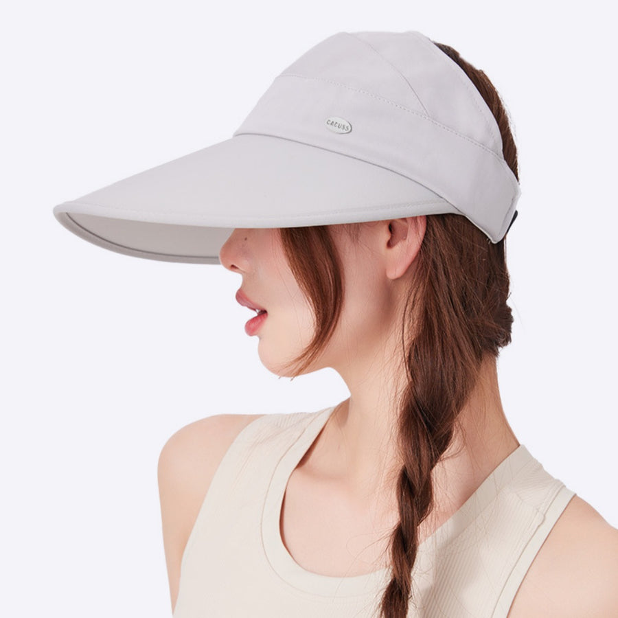 Light gray wide brim sun visor hat with button detail, worn by a woman.