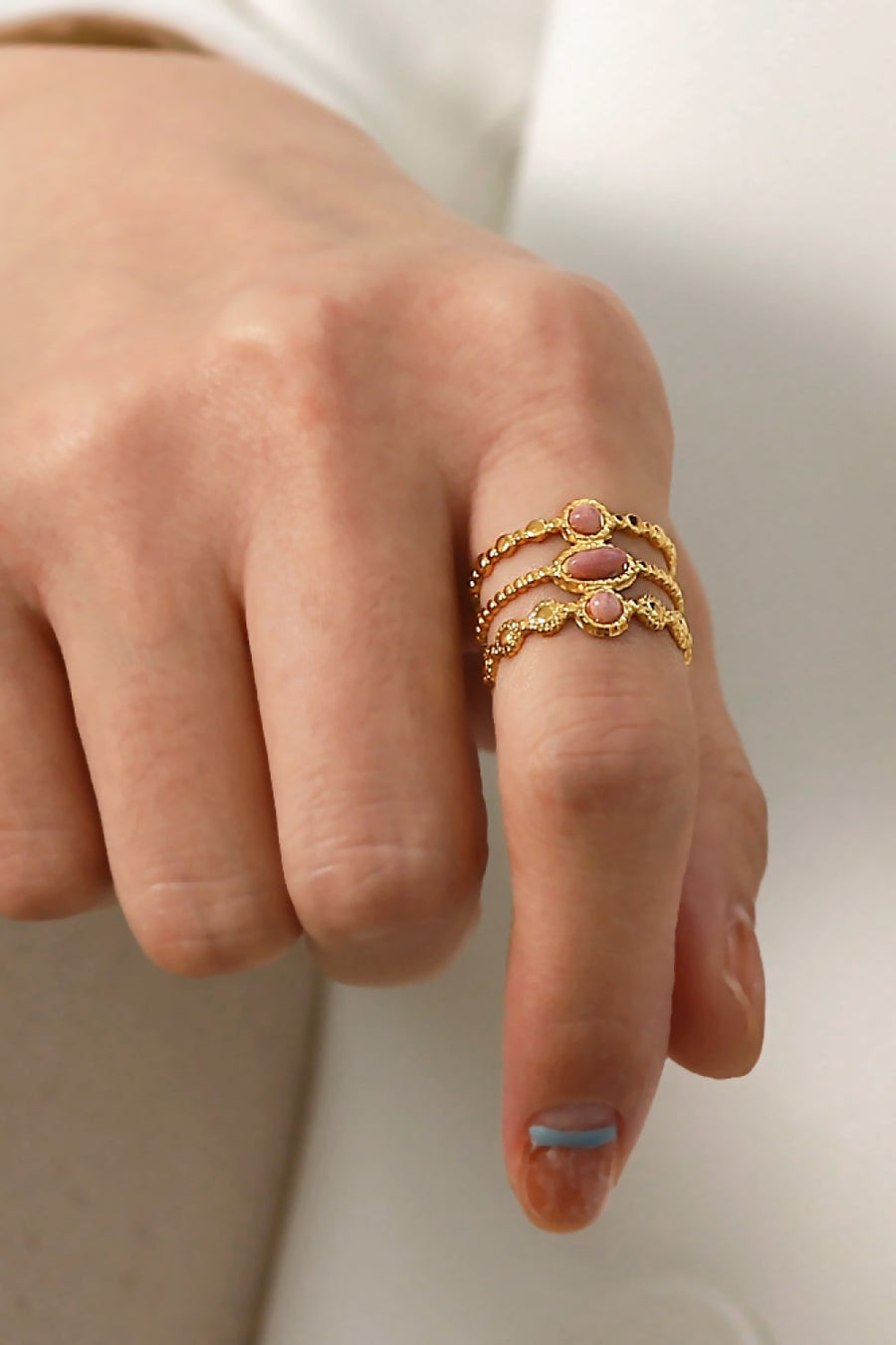 Gold triple stone openwork ring with pink stones and beaded detail.