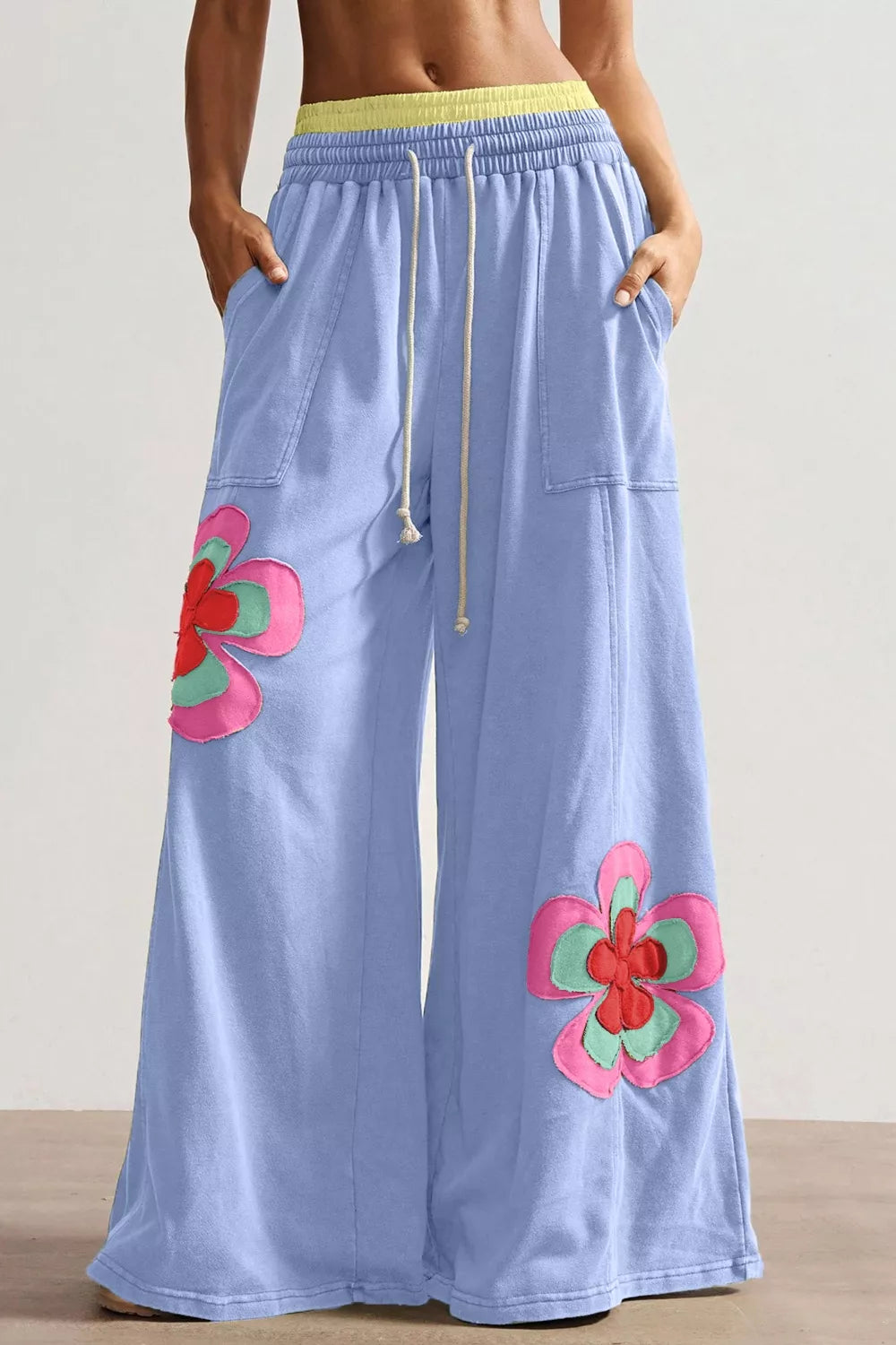 Light blue cotton maternity pants with wide legs, drawstring waist, and colorful floral appliques.