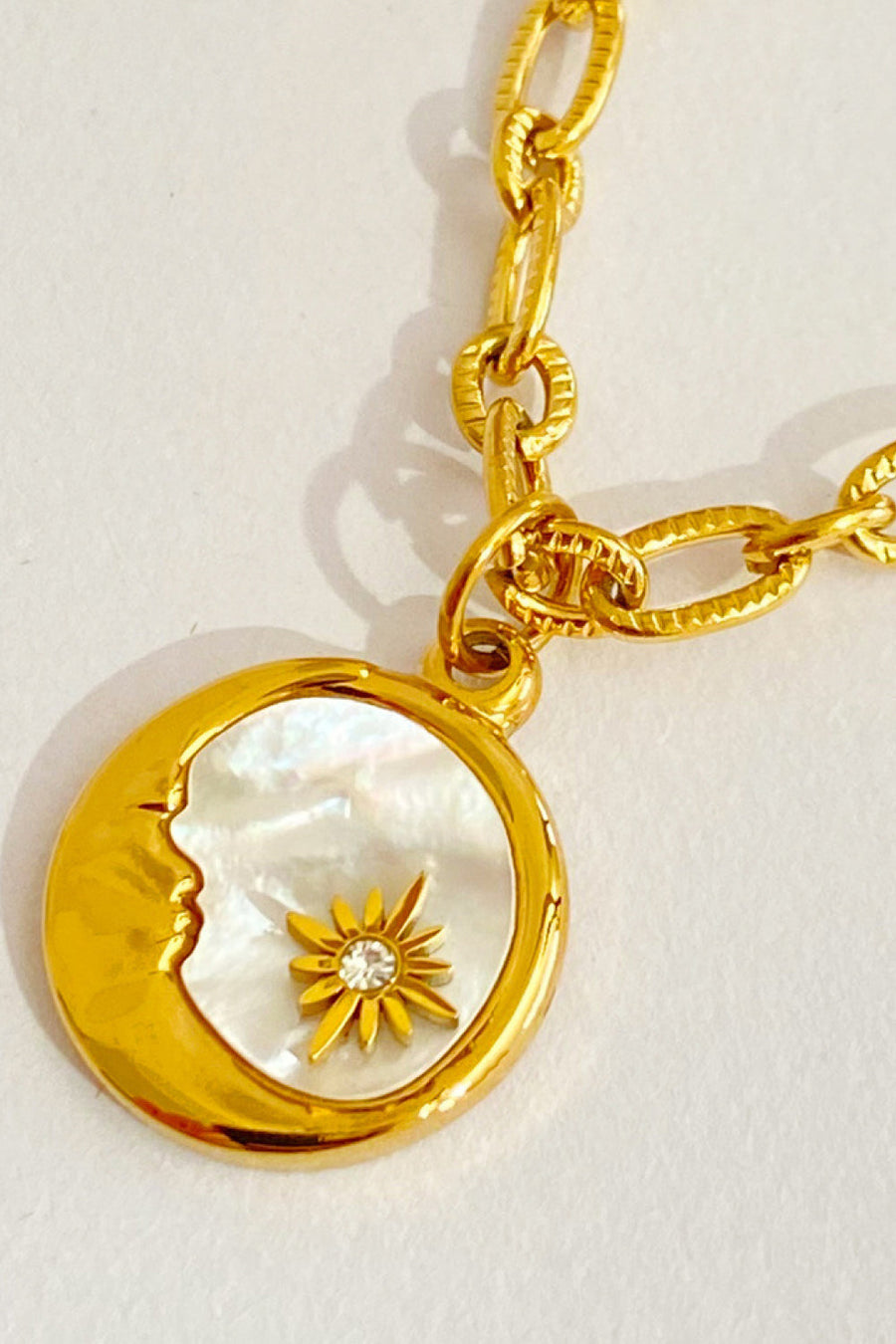 18K gold-plated chain necklace with a moon charm featuring a mother-of-pearl inlay and a sunburst accent.