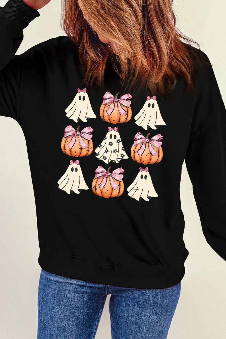 Black crewneck sweatshirt with a grid of cute Halloween ghosts and pumpkins with pink bows graphic.