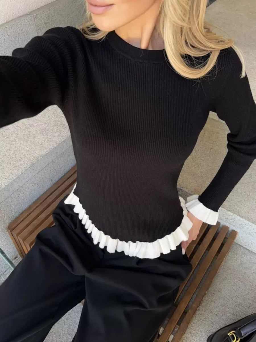 Black knit sweater with contrast white ruffled hem and cuffs.