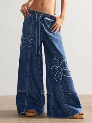 Wide leg denim jeans with floral appliques and frayed hem