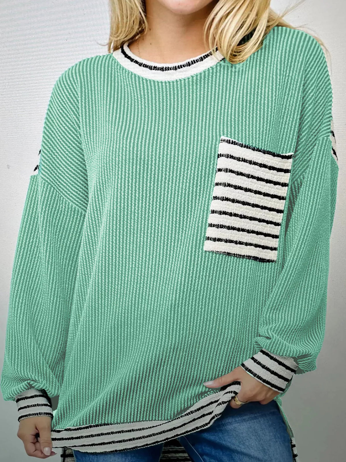 Turquoise long-sleeve top with twisted ribbing, crew neck, and striped pocket detail.