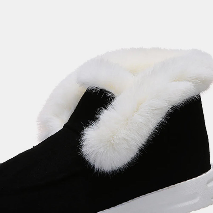Black suede slip-on booties with white shearling trim detail.