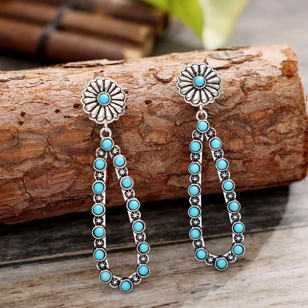 Floral turquoise bead drop earrings in silver with a flower stud and teardrop shape.