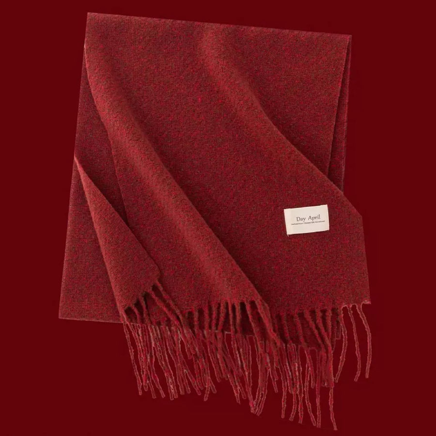 Cozy red plaid scarf with fringe detail and a small white tag.