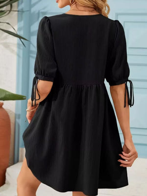 Black mini dress with puff sleeves and tie details on the cuffs.