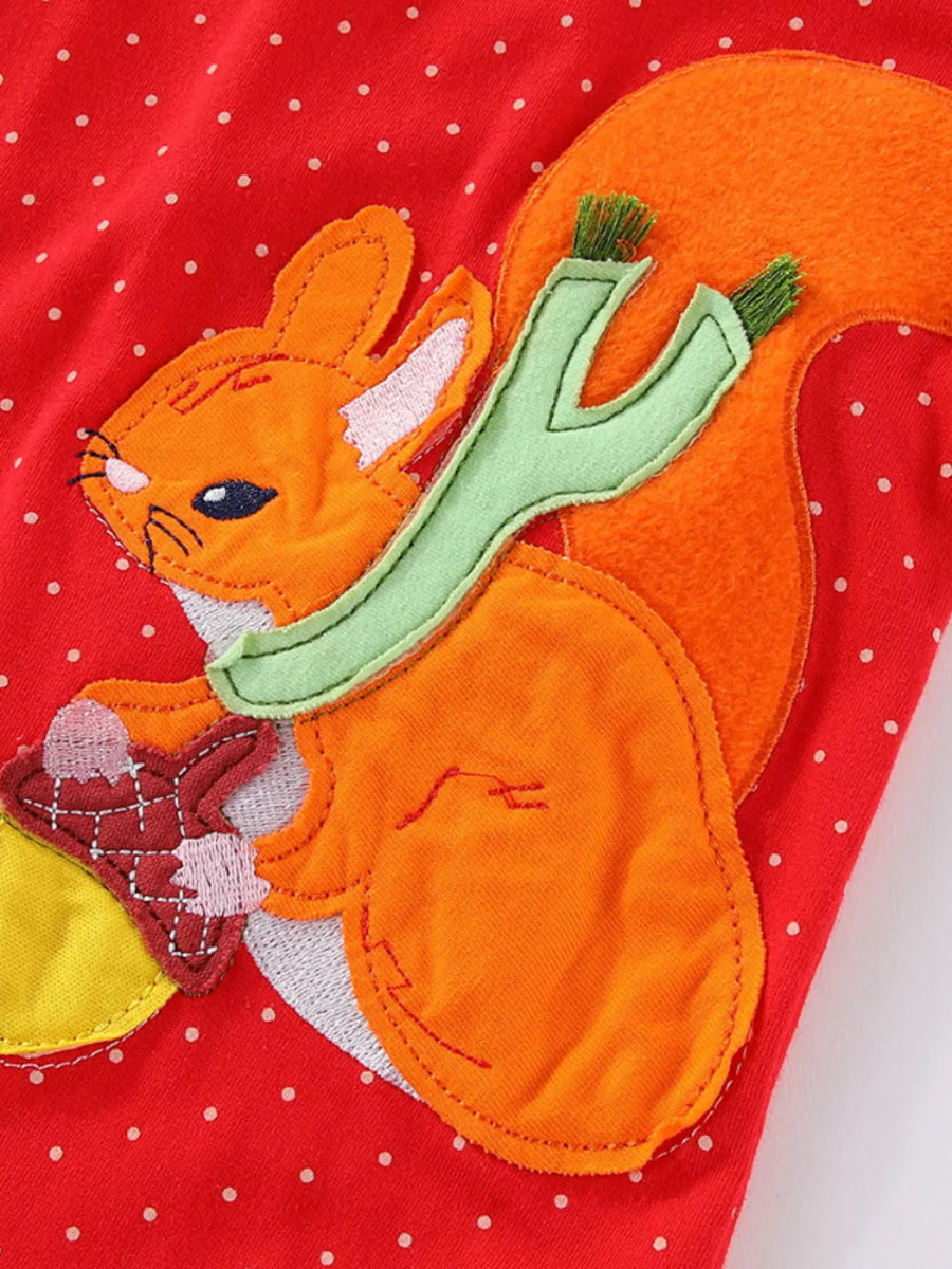 Red polka dot dress with a squirrel applique holding an acorn.