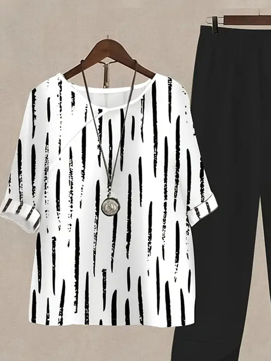 White half sleeve top with black vertical brushstroke print and black pants.