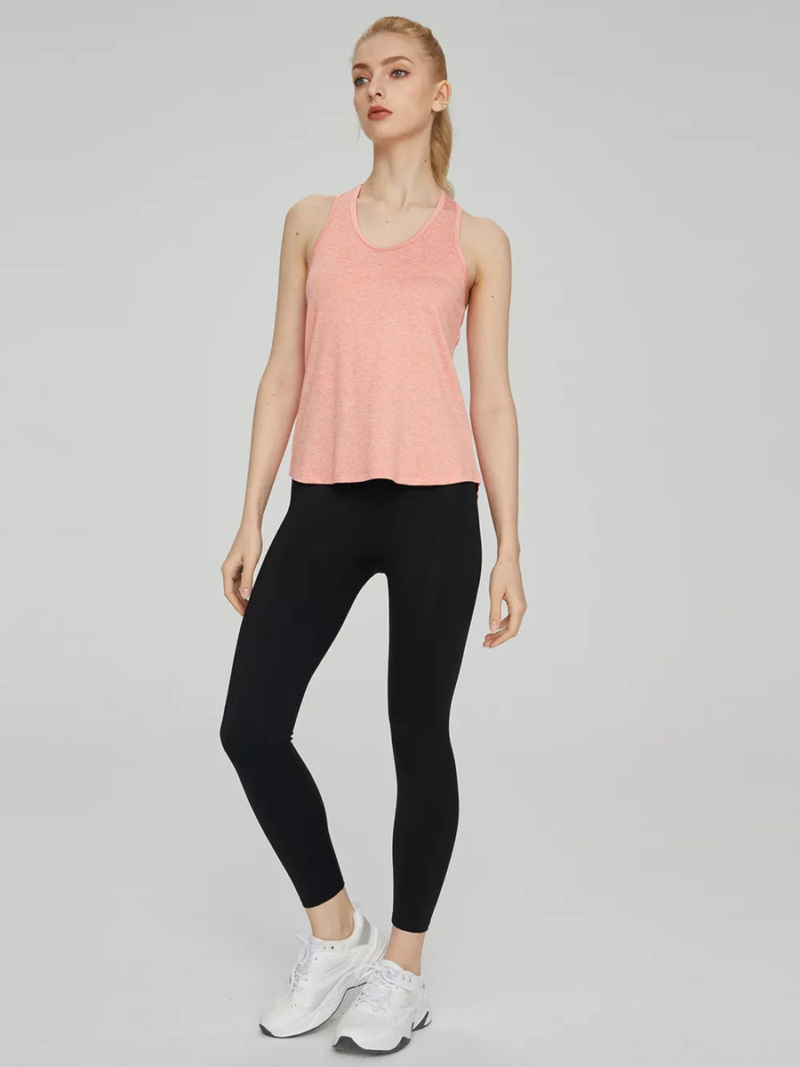 Tank top in heathered coral with racerback, paired with black leggings and white sneakers.