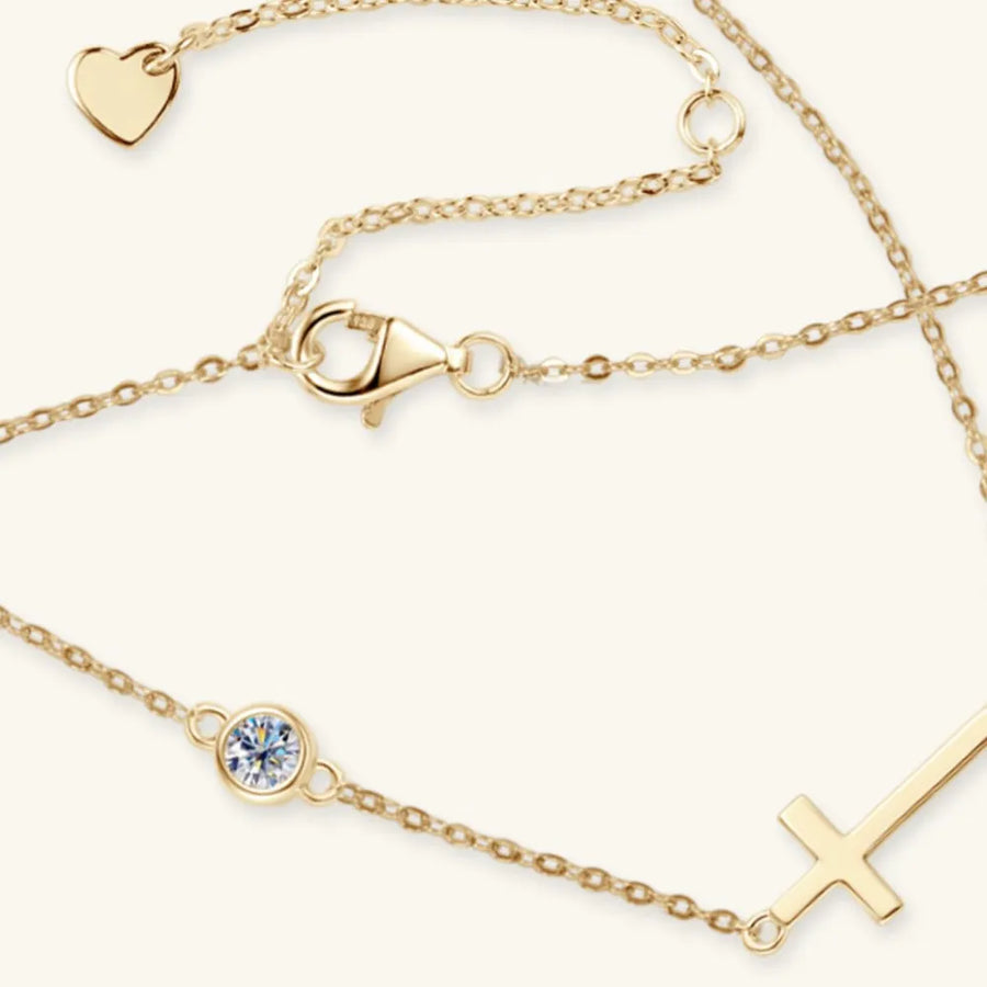 Gold asymmetrical cross pendant necklace with a delicate chain and a single crystal accent.