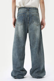 Oversized patchwork distressed denim trousers in medium wash, featuring a baggy fit and wide leg.