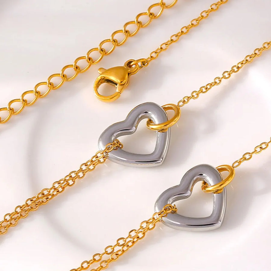 Two-tone heart charm bracelet with gold chain and clasp.