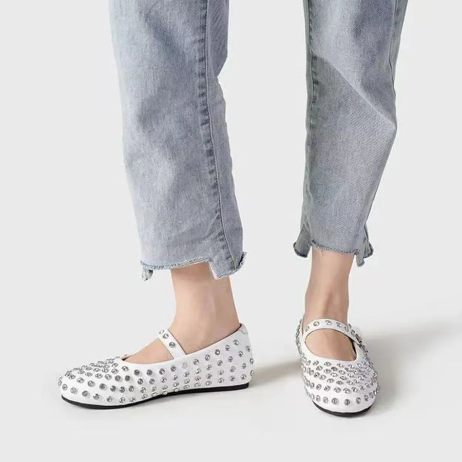 White studded Mary Jane flats with ankle strap and buckle detail.