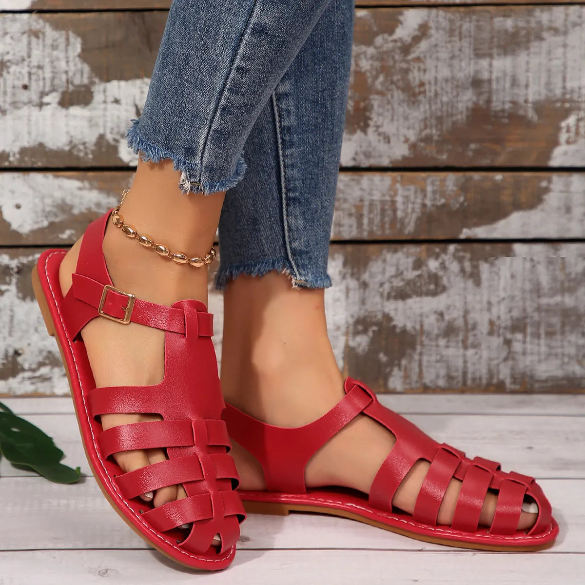 Red woven leather t-strap sandals with buckle detail and open toe.