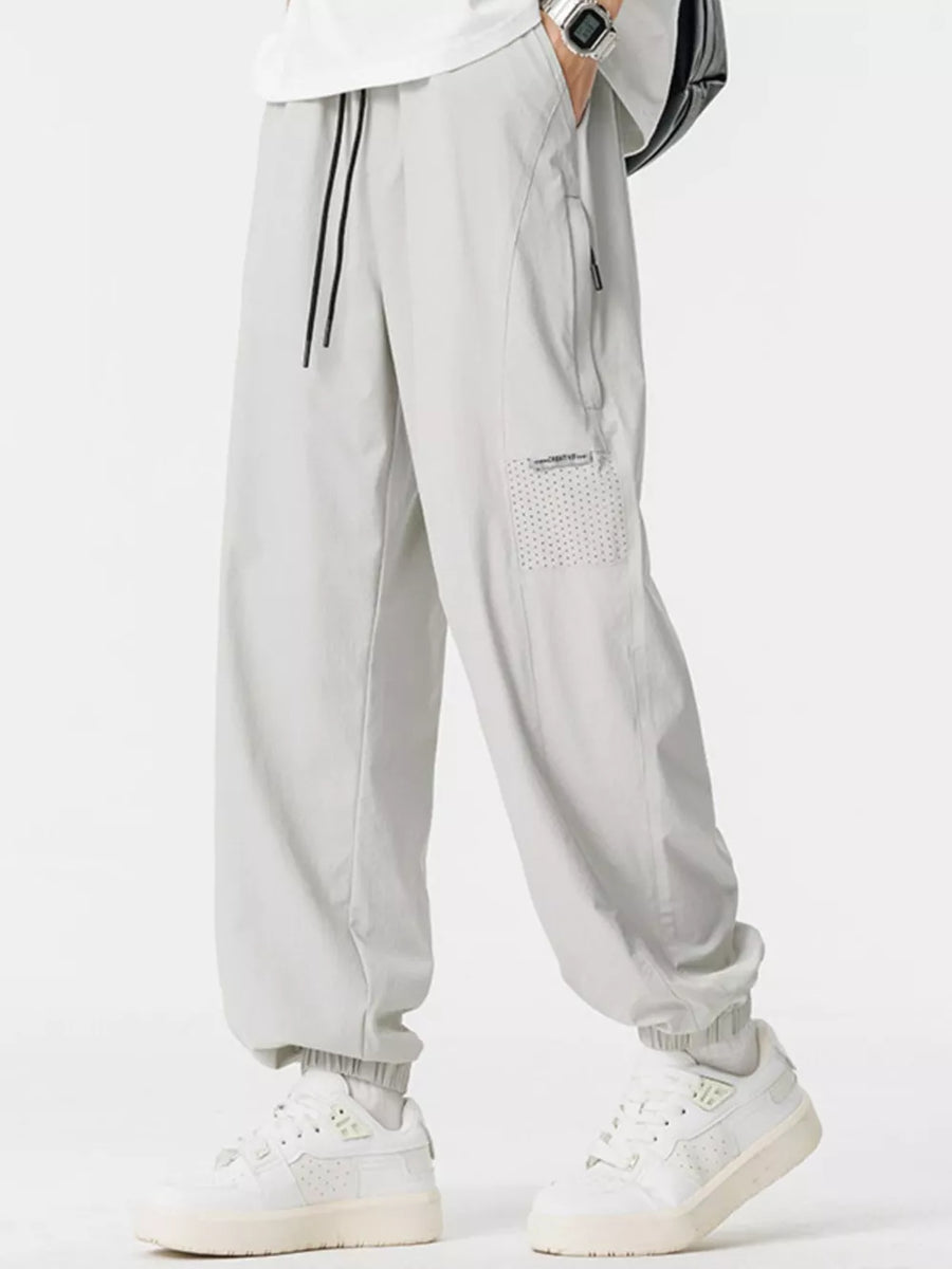 Lightweight grey jogger sweatpants with drawstring and zippered pocket detail.