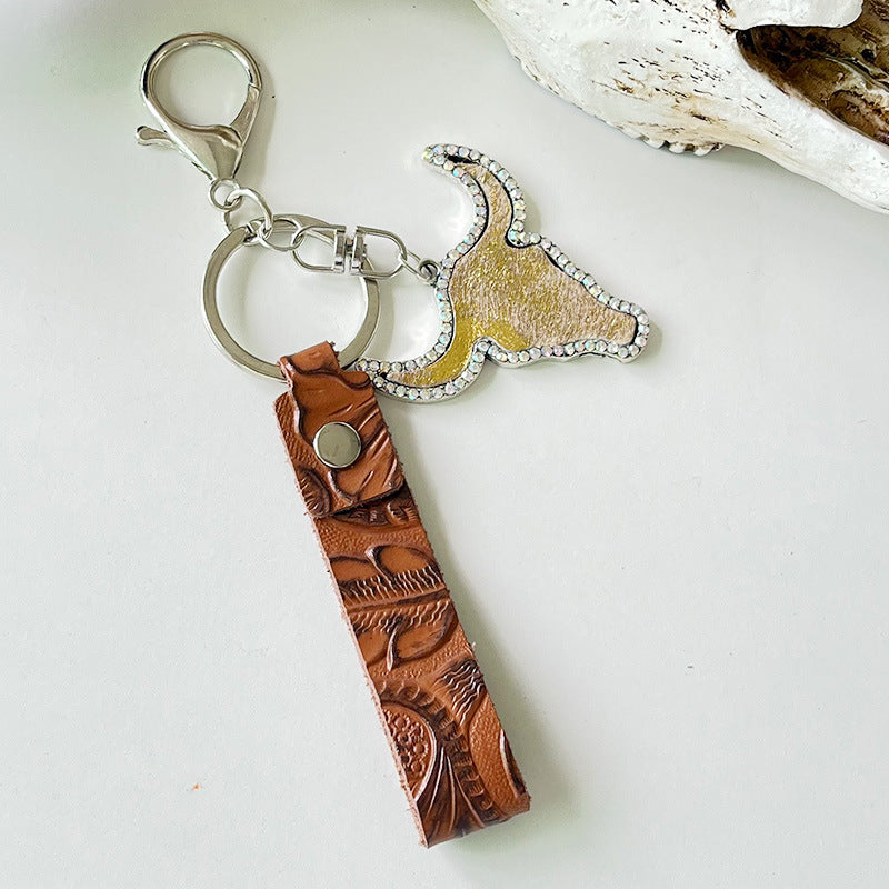 Western-inspired keychain with bull skull charm, crystals, and tooled leather strap.