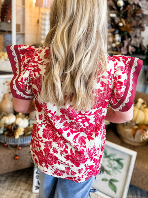 Floral print blouse with lace trim on short sleeves, red and white pattern.